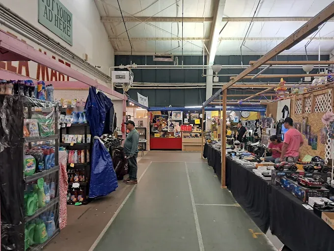 a raynham flea market aisle with stalls on both sides. left, shelves of cleaning products. right, various items on tables