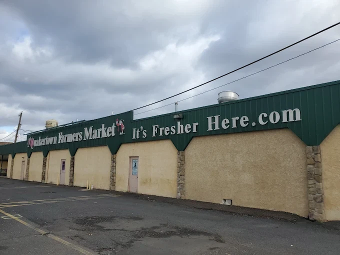 exterior of quakertown farmers market and flea market featuring a beige building with a green roof line and its fresher here.com signage.