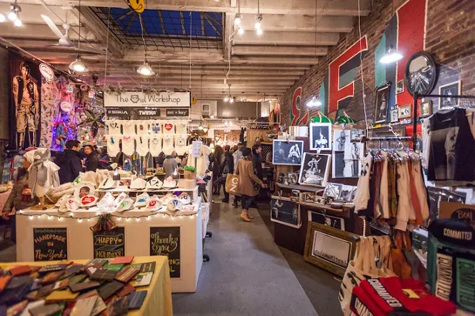 bustling indoor market showcasing diverse handmade goods, art, and clothing. shoppers browse colorful stalls under warm lighting, creating a lively atmosphere.