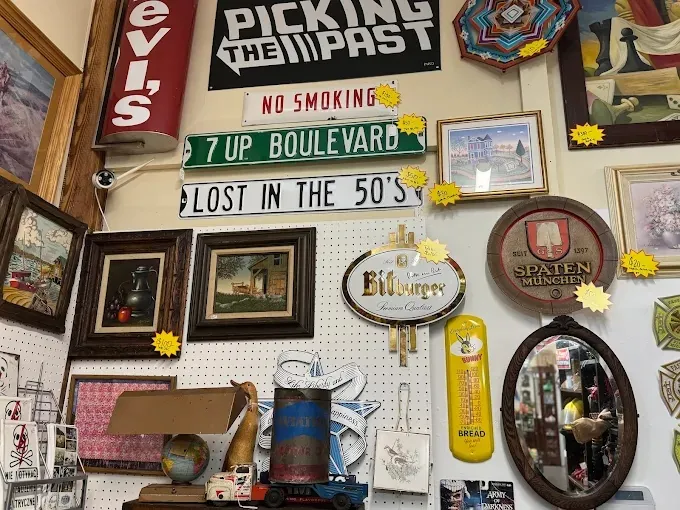 A pegboard wall decorated with vintage signs like 7 UP Boulevard, framed art, and a round Spaten München sign at benningtons antique center