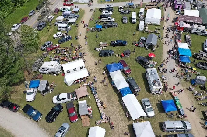 aerial view of a bustling outdoor market with numerous stalls under white and blue tents.