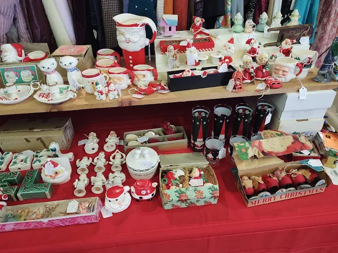 festive display of vintage christmas decorations on shelves, including santa mugs, figurines, and colorful ornaments, evokes a nostalgic holiday vibe at burton antiques show