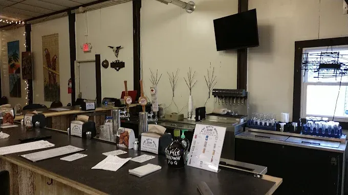 flea market at the rock cozy bar with a rustic wooden counter, assorted taps, drink menus, and bottle displays. dim ambient lighting and a wall-mounted tv enhance the relaxed area