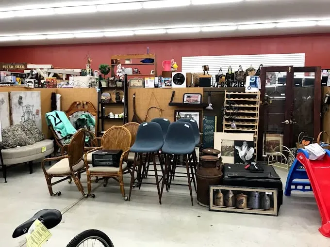 interior displays a mix of furniture and decor items, including wicker chairs, blue stools, and vintage items, creating an eclectic and nostalgic vibe a funky munky flea market.