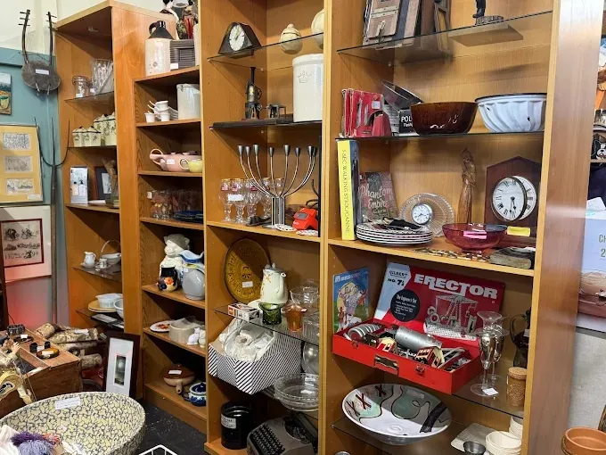 tall wooden shelving units displaying vintage kitchen items, clocks, and an erector set box.