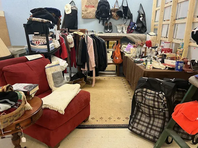 This market room is filled with assorted clothing, a red armchair, backpacks, and miscellaneous housewares.